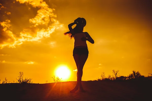 Silhouette of a young girl in a shirt and shorts holds over his — Stockfoto