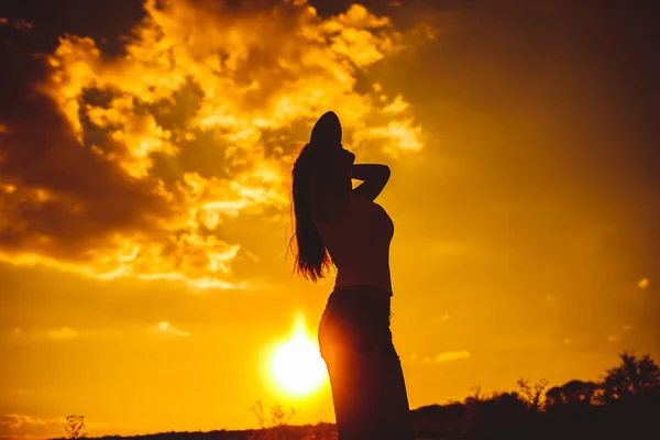 Silhouette of a young girl in a vest and shorts arm straightens — ストック写真