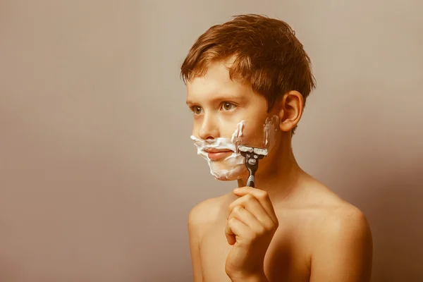Teenage boy 12 years of European appearance with a razor shaves — Stock Photo, Image