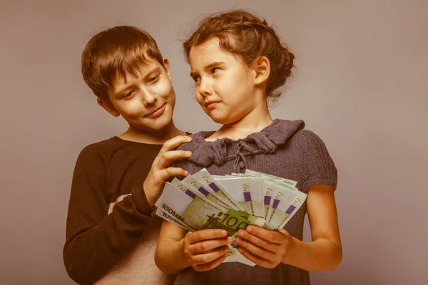 Teenage boy and girl holding money bills in his  hands on a  gra — Stock Photo, Image
