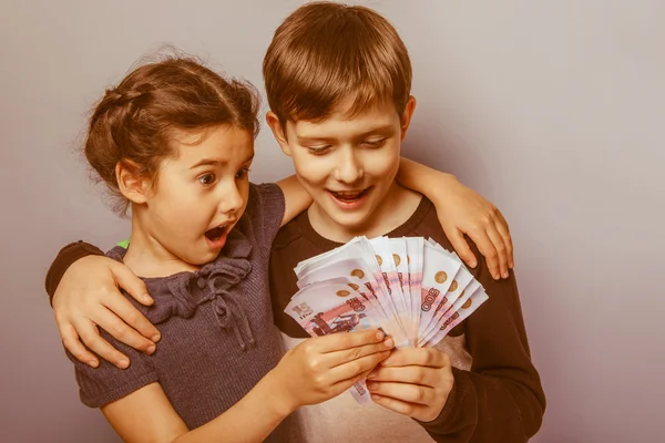 Teenage boy and girl holding money bills in his hands on a gray — Stock Photo, Image