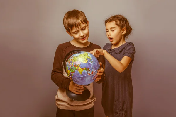 Teenage boy with a girl looking at a globe girl opened her mouth — Stock Photo, Image