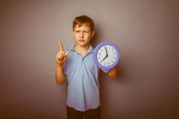 Adolescente ragazzo marrone aspetto europeo tiene un orologio che mostra gio — Foto Stock