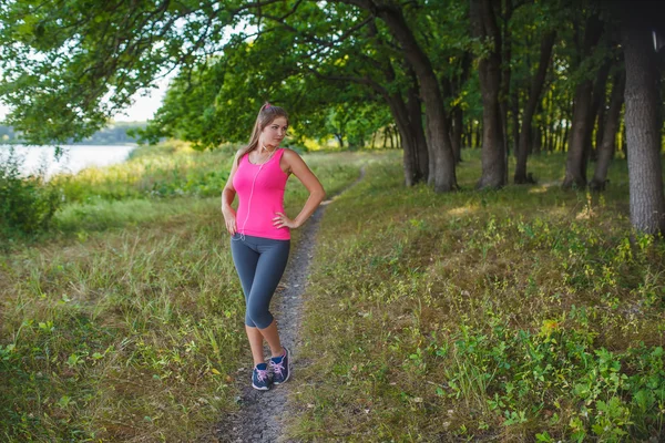 Young woman of European appearance in a pink shirt and gray tigh — Stockfoto