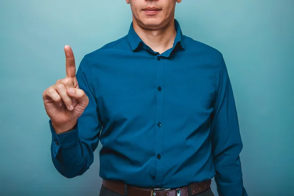 Un hombre con una camisa azul levantó su dedo índice sobre un fondo gris —  Fotos de Stock