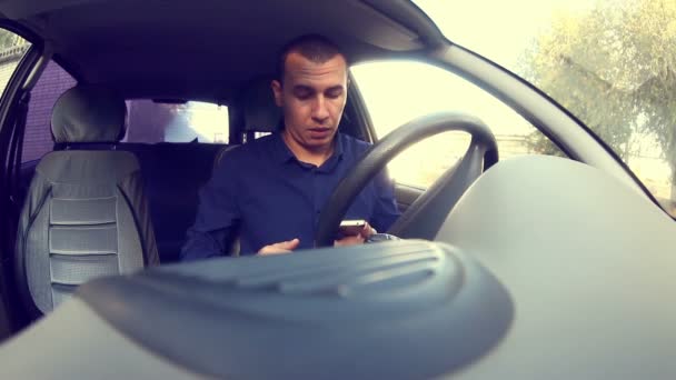 Менеджер мужчина сидит в машине с мобильным телефоном в руке смс во время вождения — стоковое видео