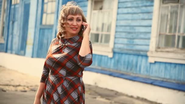 Gruesa mujer de mediana edad gorda hablando por teléfono fuera de un fondo azul es una casa vieja un estilo de vida — Vídeo de stock