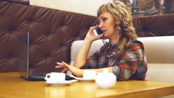 De vrouw aan de telefoon werken op een laptop in een café dikke vette gemiddelde leeftijd van levensstijl — Stockvideo