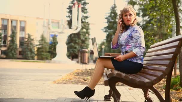 Žena středního věku plná tuku sedícího na lavičce v parku práce v přenosném počítači nezávislý pracovní podnik vítr — Stock video