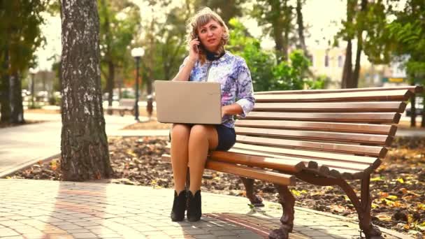 Mulher de meia-idade cheia de gordura sentado no banco do parque vento de trabalho no laptop freelancer negócio de trabalho distante — Vídeo de Stock