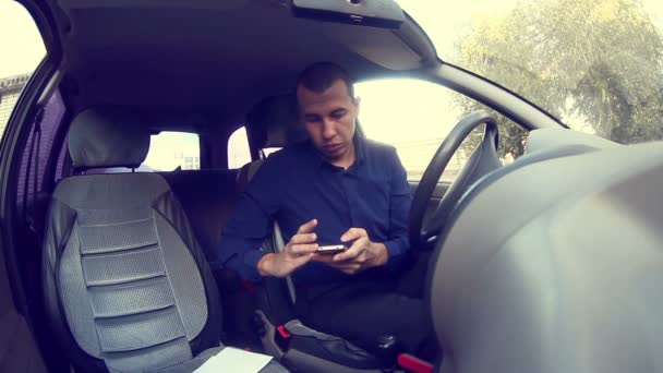 Joven hombre guapo hombre de negocios utilizando el teléfono de pantalla táctil móvil en el coche — Vídeo de stock