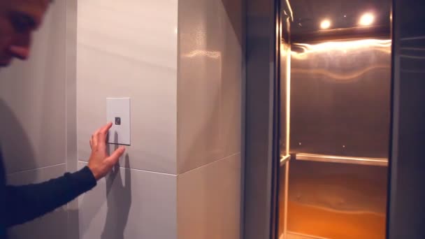 De man roept een moderne lift op en komt in het een trui en jeans avond — Stockvideo