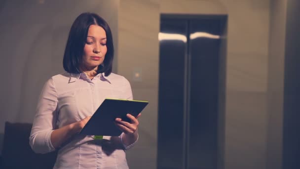 Mujer joven gerente de hotel de negocios en un ascensor con una Tablet PC — Vídeo de stock