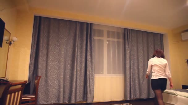Pohled zezadu mladá žena zaměstnance správce otevře záclony na okno pro otevření hotelového pokoje