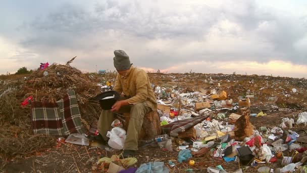 Ember hajléktalan koldus ül egy hulladéklerakó egy kalap kér pénzt élelmiszer hulladék teherautó túrák — Stock videók