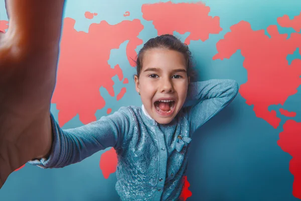 Girl teen shouting stretched her arms behind world map background education — Stock fotografie