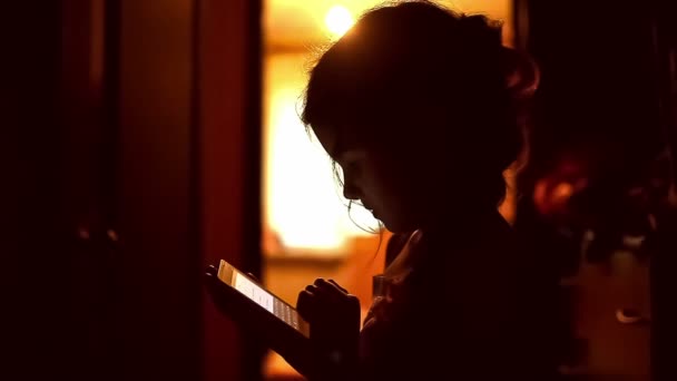 Подростковая девушка смотрит игры смартфон в Интернете в коридоре крытый желтый коричневый силуэт — стоковое видео
