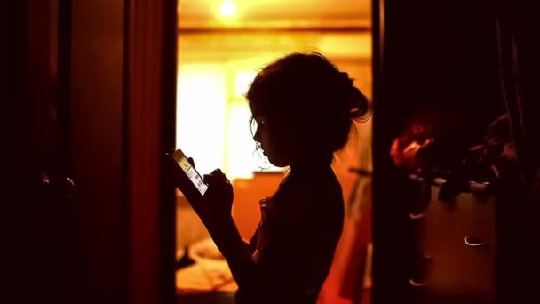 Mädchen Teenager suchen Smartphone-Spiel im Internet im Flur Indoor gelb braun Silhouette — Stockvideo