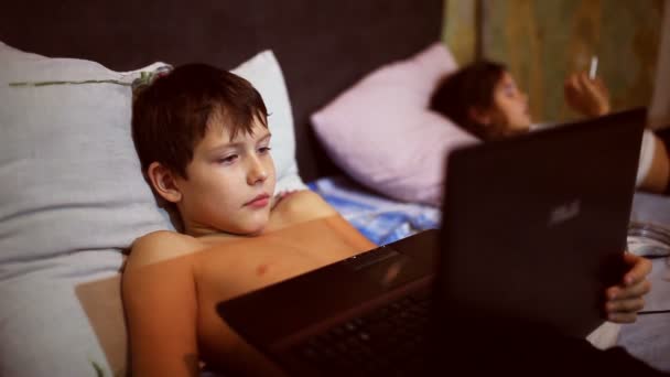 Adolescente garoto jogando computador jogos laptop notebook deitado em sua cama à noite — Vídeo de Stock