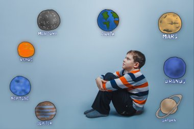 boy sitting frowned and hugged her knees looking at the planets