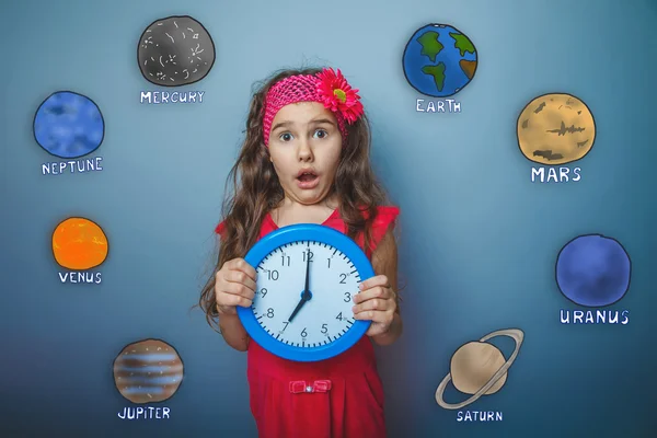 Girl made a surprised face holding a clock planet of the solar s — Stock Fotó