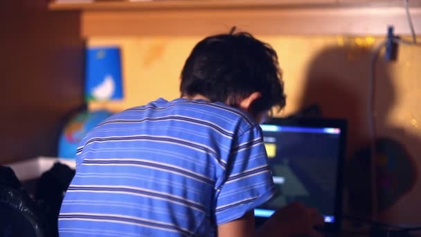 Tiener jongen spelen computer video game zittend terug avond kamer — Stockvideo