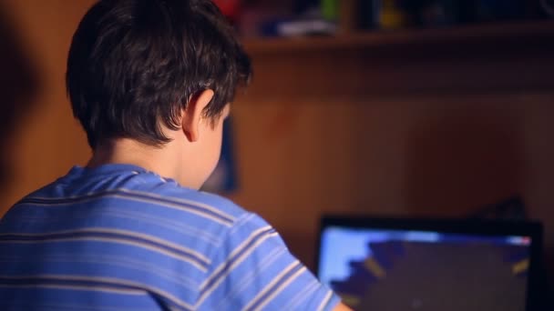 十代の遊び少年コンピュータビデオゲームは、後ろに夜の部屋に座って — ストック動画