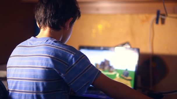 奥の部屋に座っているコンピューター ゲームのビデオを再生する 10 代の少年の夜 — ストック動画