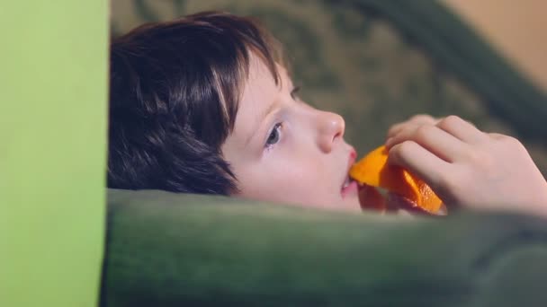 Teenage boy is eating an orange and peel — Stock Video