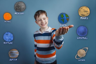 Teen boy holding hands and smiling at the planet of the solar sy