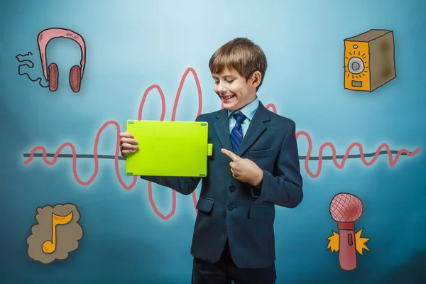 Boy in a business style suit laughs and points to the tablet in — Zdjęcie stockowe