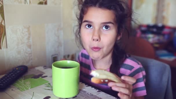 Teen girl eats bread with butter tea drinkers breakfast — Stock Video