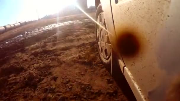 Car auto goes through puddles and mud sun glare on water — Stock Video