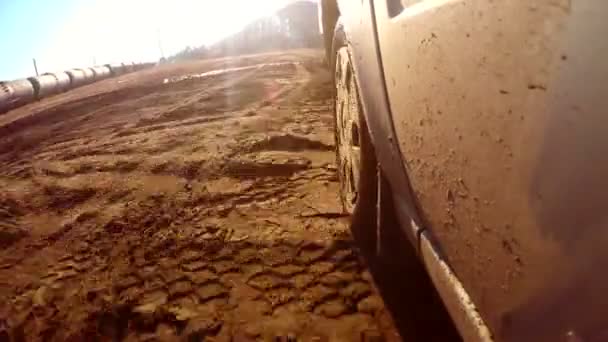 Auto bil går igenom vattenpölar och lera solen reflexer på vatten — Stockvideo