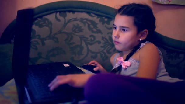 Девочка-подросток, играющая в ноутбук, лежащий на диване — стоковое видео