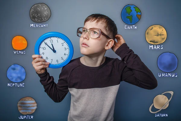 Adolescente chico arañando su cabeza sosteniendo reloj de mano y mirando u — Foto de Stock