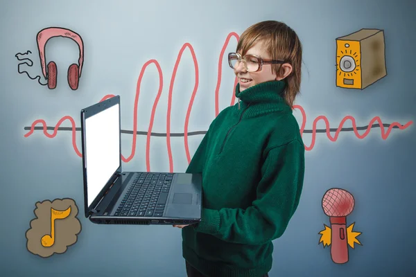 Adolescente en suéter verde y gafas sostiene un ordenador portátil y laug — Foto de Stock