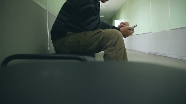 Muž student na internetu s smartphone, telefon, sedí na židli v hale univerzity — Stock video