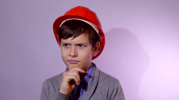 Teen pojke builder i orange hjälm jag tror problemet studio porträtt — Stockvideo