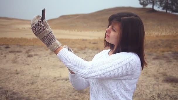 Vrouw meisje smartphone maakt zelf telefoon wanten pullover zittend op droge boom natuur herfst — Stockvideo
