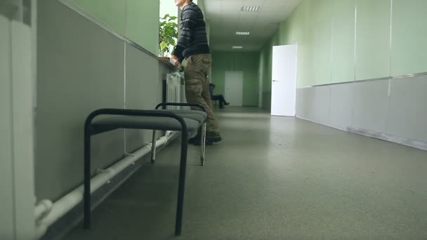 Man student står vid fönstret smartphone Wi Fi ingår i korridoren universitet — Stockvideo