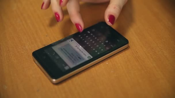 Mujer escribiendo sms en el teléfono inteligente en la mesa de cerca — Vídeos de Stock