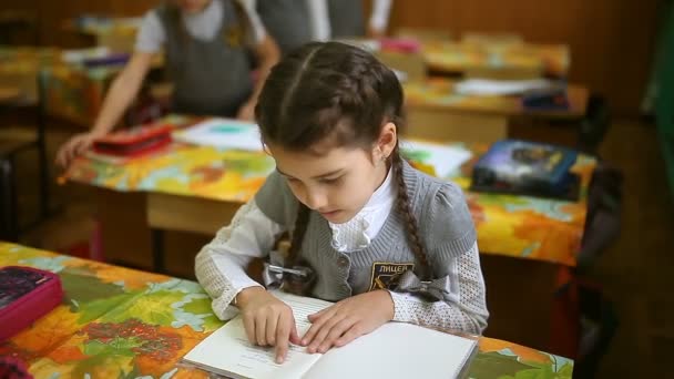 Flicka tonåring läste boken skolflicka sitter vid ett skrivbord i en klassrummet skola — Stockvideo