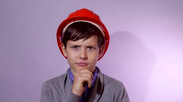 Adolescente niño constructor en casco naranja Creo que el retrato de estudio problema — Vídeo de stock