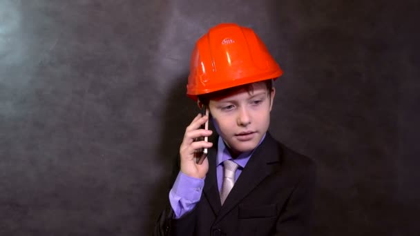 Підліток портрет хлопчик будівельник в шоломі посміхається говорити по телефону смартфон — стокове відео