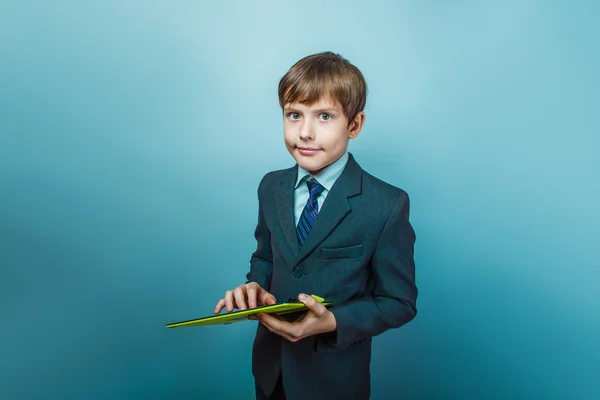 Teen boy of twelve European appearance in a business suit holdin — Stock Photo, Image