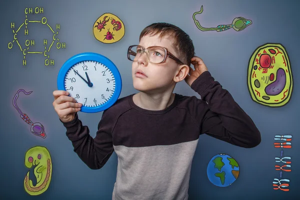 Teenage boy in glasses holding a clock hand and scratching his h — 图库照片