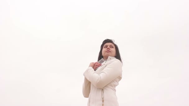 Mujer retrato chica en abrigo en blanco otoño fondo viento — Vídeos de Stock