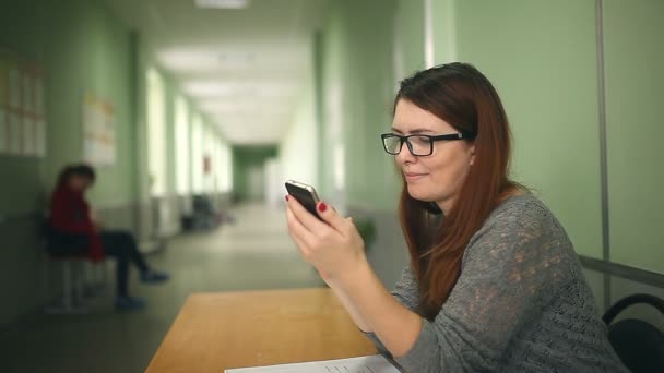 Vrouw meisje houden slimme telefoon zoeken op het internet zitten in school corridor — Stockvideo