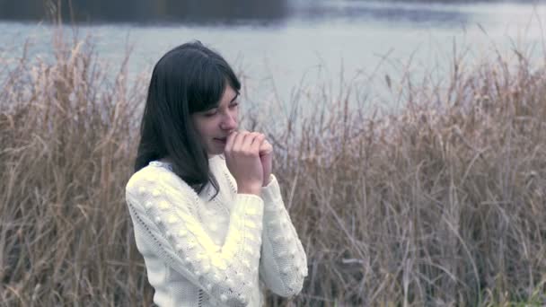Mujer chica frío frota sus manos en blanco chaqueta de hierba seca — Vídeo de stock